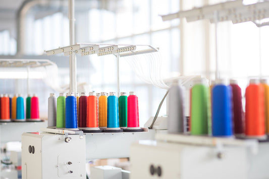 Sewing machine with colorful threads for eco-friendly apparel manufacturing in a sustainable fashion production process.